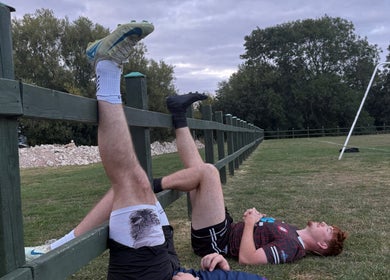 Two athletes resting on grass near Sport Spa Ltd, London, England, GB.