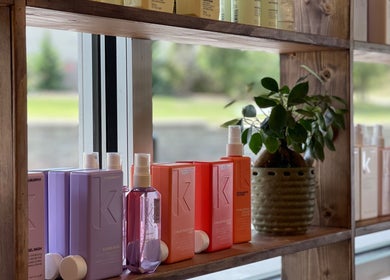 Colorful hair products on wooden shelf at Alora Salon, Pittsburgh, Pennsylvania, US, displaying a fresh touch.