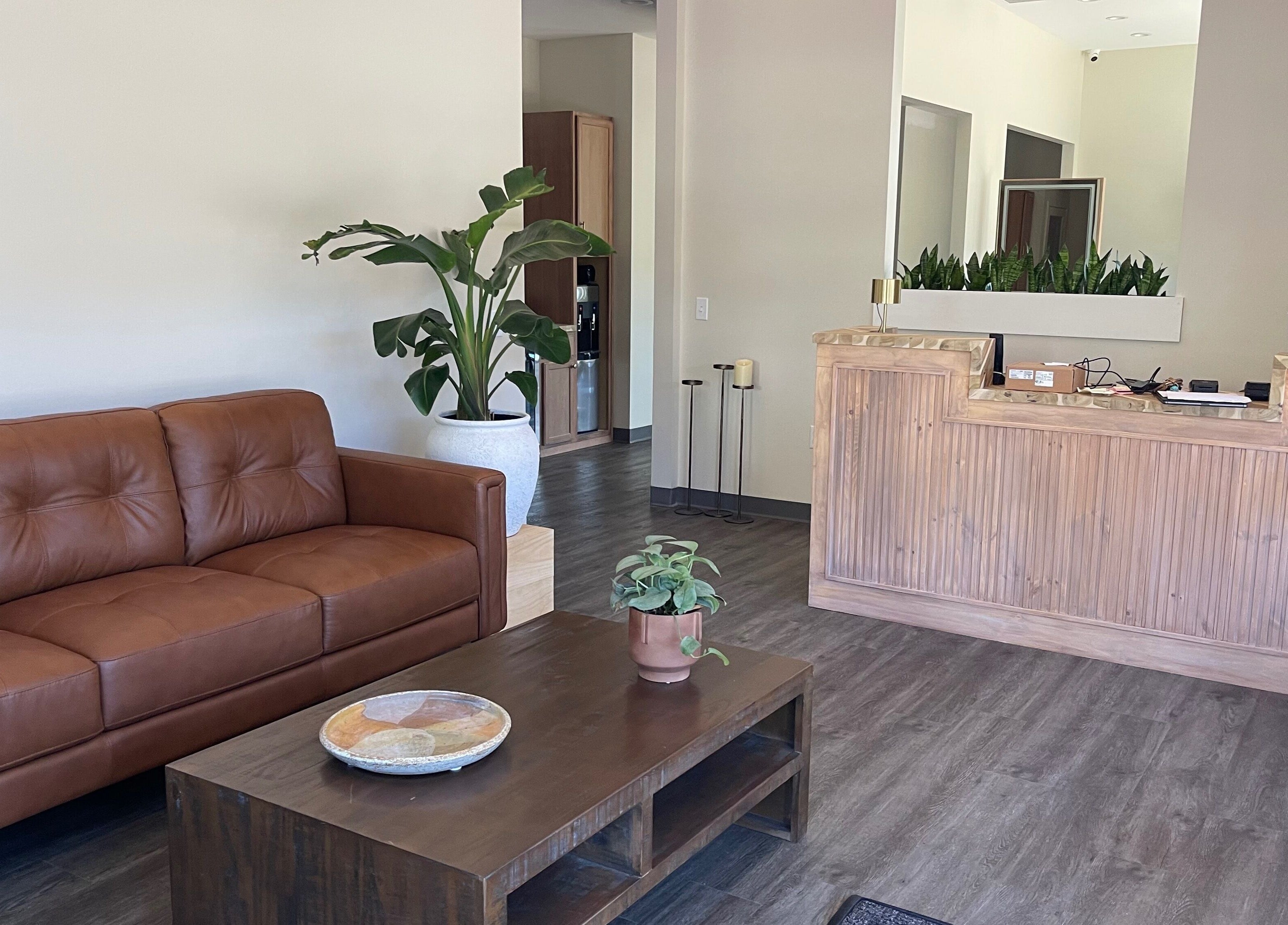 Cozy reception area at Alora Salon, Pittsburgh, Pennsylvania, US featuring a leather sofa and wooden desk.