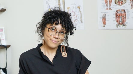 Therapist at Good Moon Bodywork (Jaz Frazier, LMT) with anatomical charts in Buffalo, New York, US.