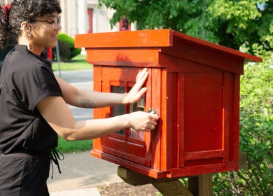 Person at red community cupboard near Good Moon Bodywork (Jaz Frazier, LMT), Buffalo, New York, US.