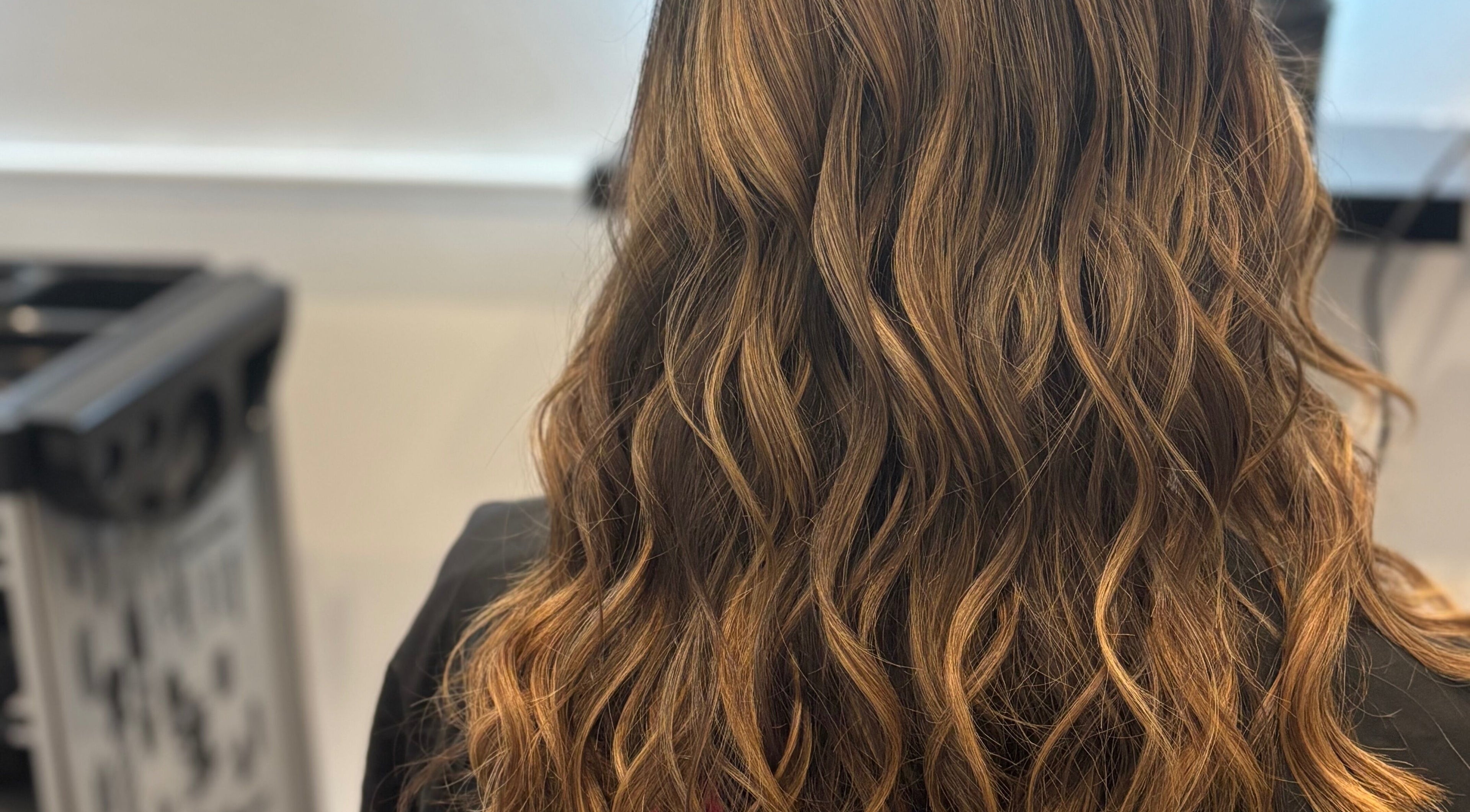 Close-up of wavy brown hair styled at The Little Hair Room, Ayr, Scotland, GB, showcasing texture and shine.