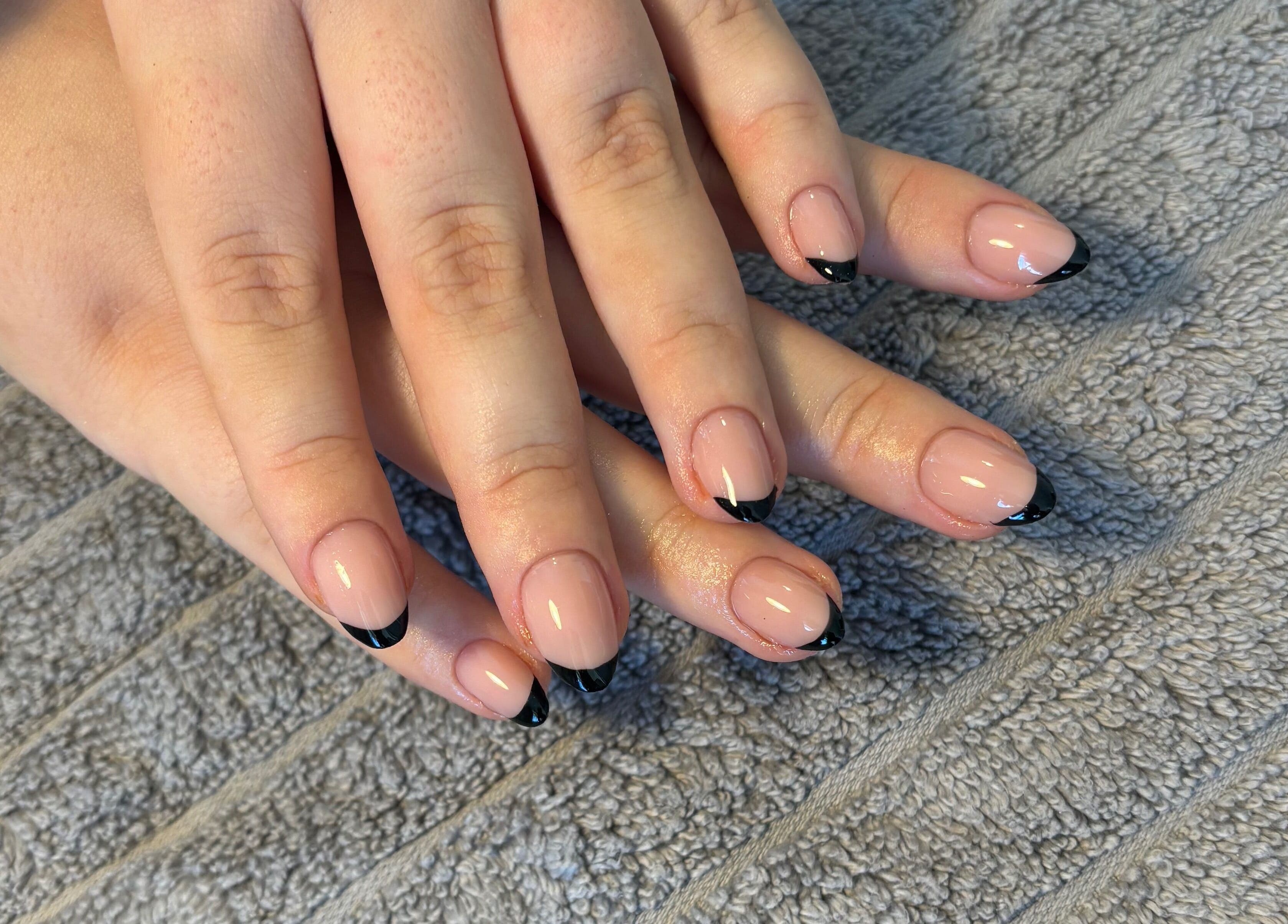 Elegant black-tipped nails by Nailsbyebonyy in Rainham, England, GB, displayed on a textured surface.