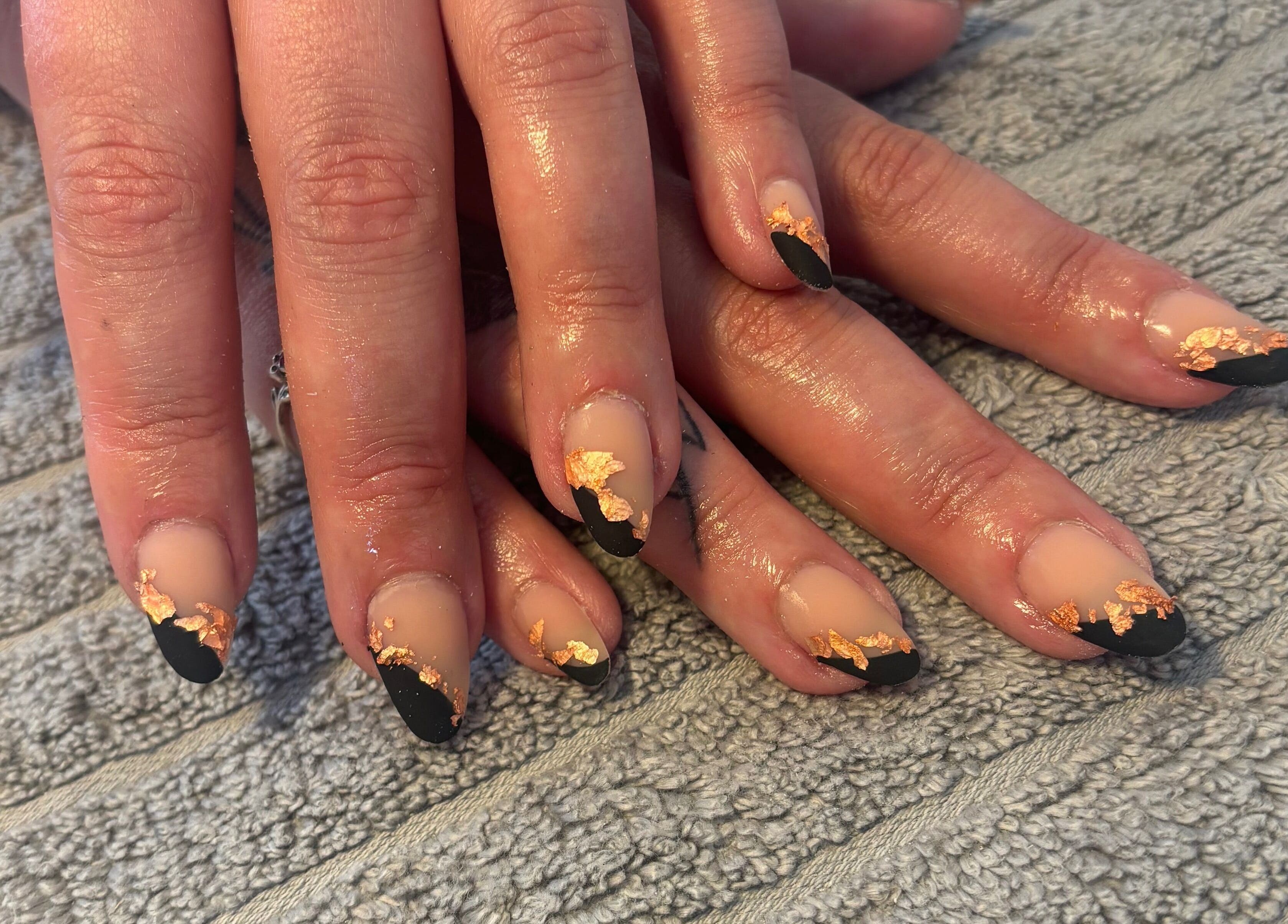 Elegant nail art with gold leaf and black tips at Nailsbyebonyy, Rainham, England, GB.