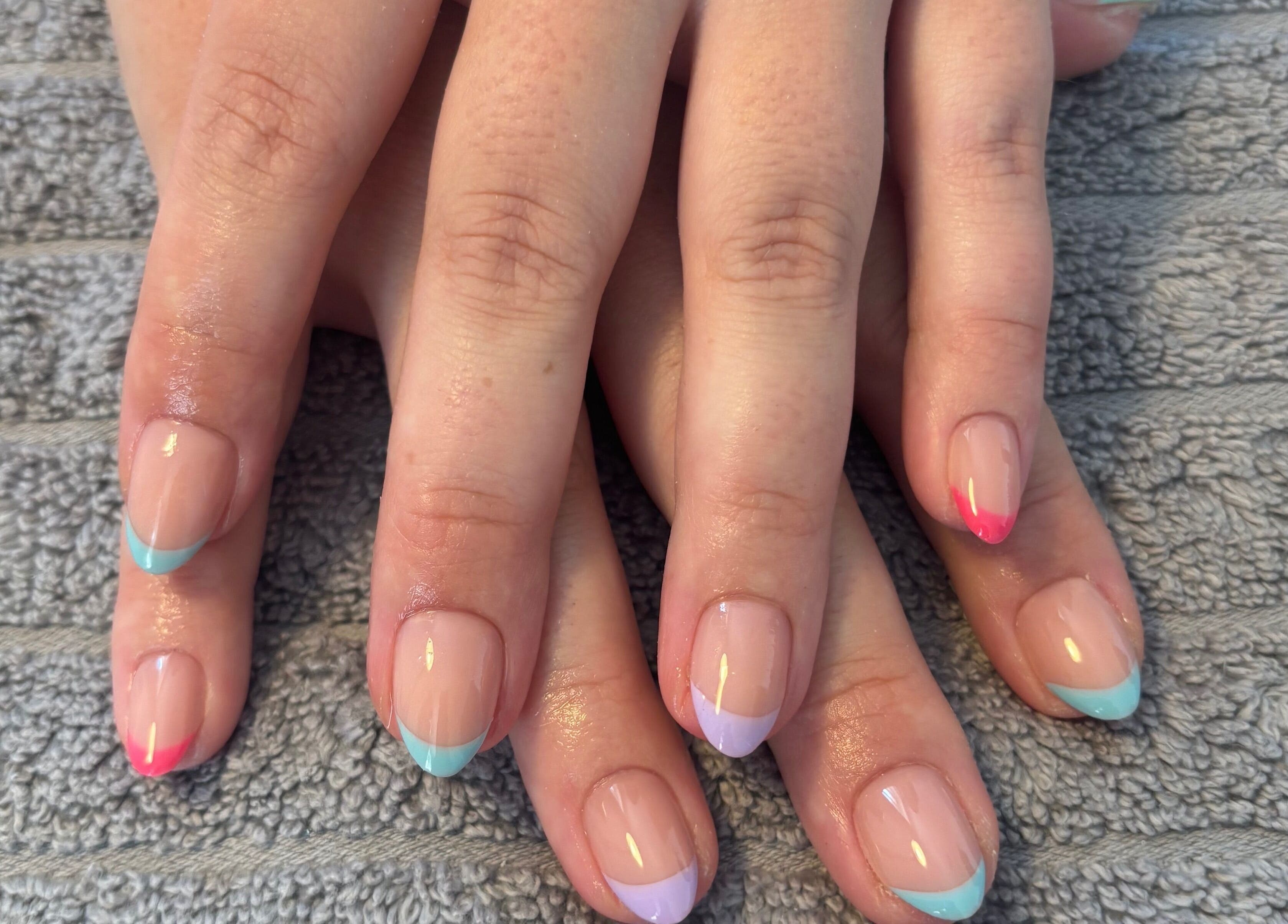 Colorful French manicures at Nailsbyebonyy, Rainham, England, GB showing vibrant nail art on a towel.