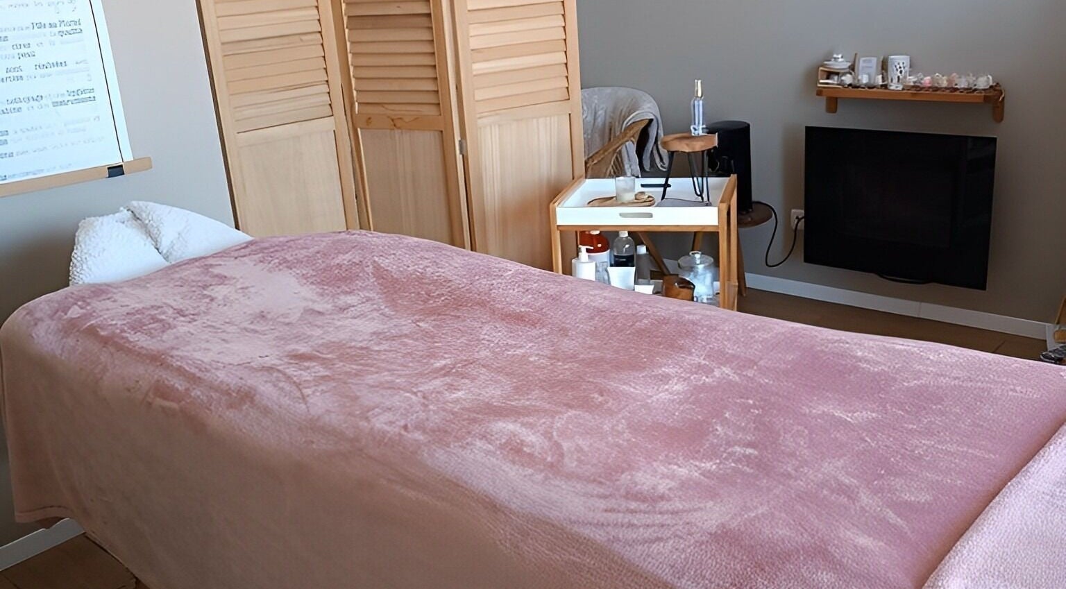 Salle de massage accueillante à Instants d Evasion, La Vacherie, Normandie, FR avec couverture rose et équipements spa.
