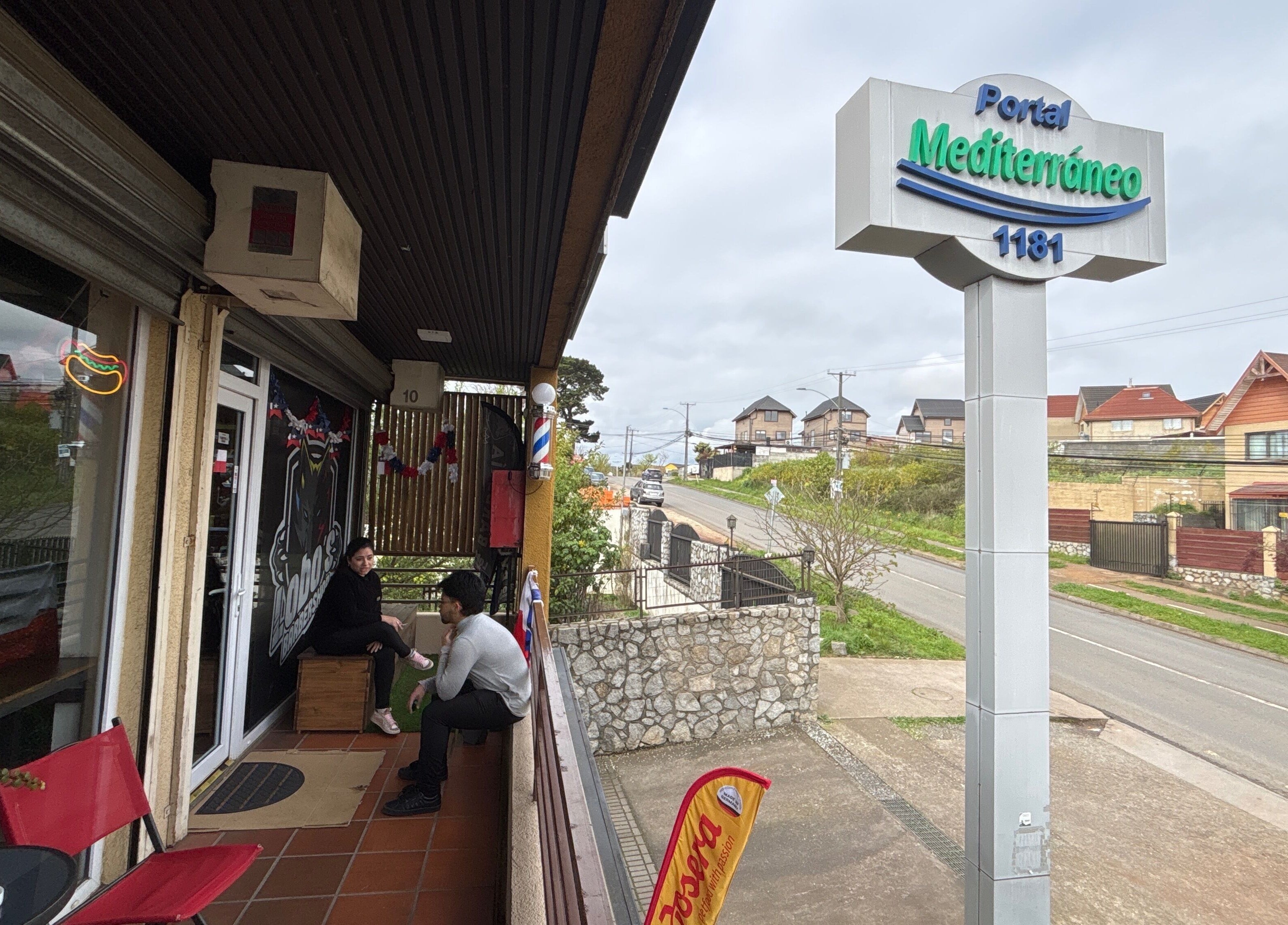 Entrada del Lobosbarbershop en Concepción, Bío Bío, CL, mostrando áreas exteriores y letrero del Portal Mediterráneo.