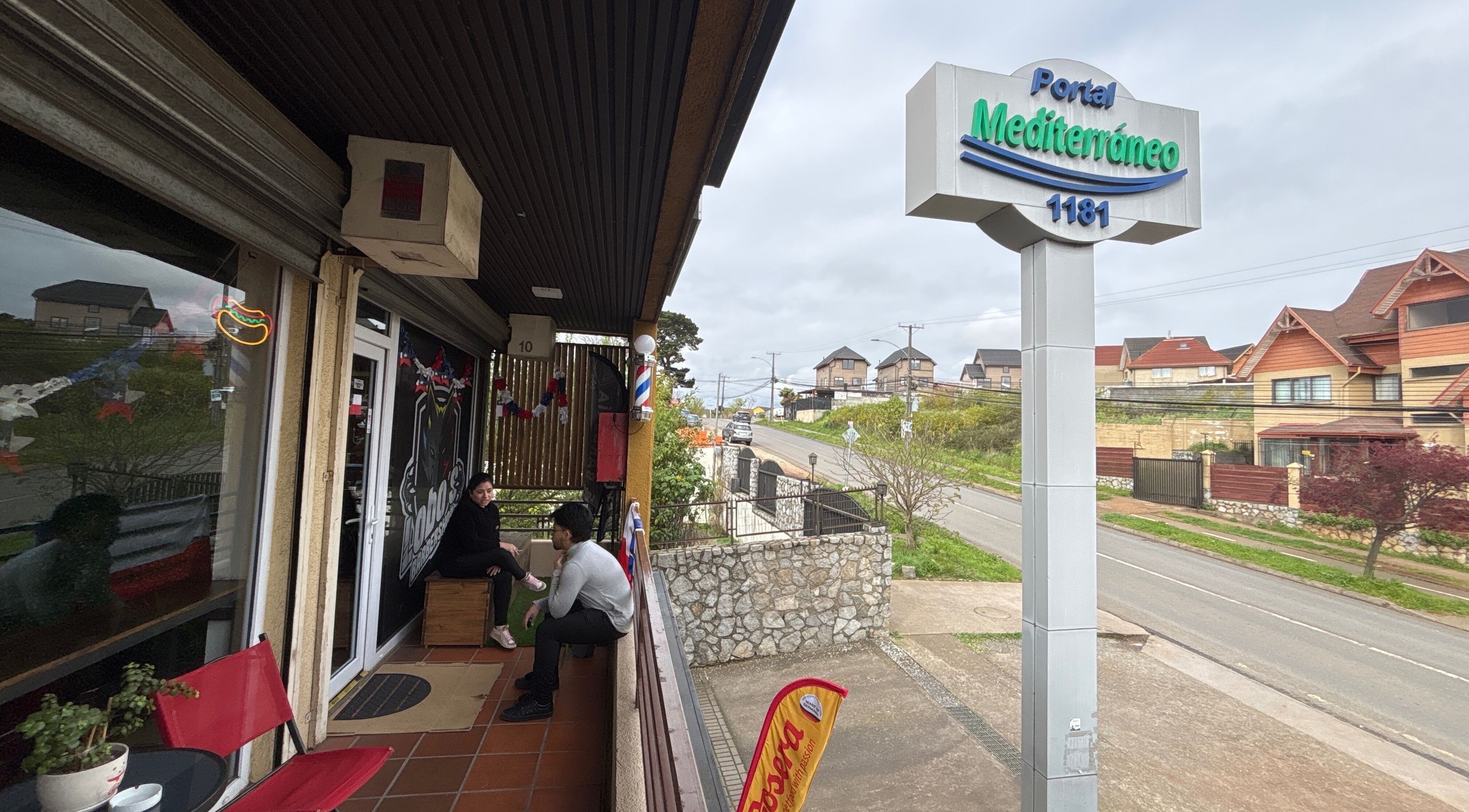 Entrada del Lobosbarbershop en Concepción, Bío Bío, CL, mostrando áreas exteriores y letrero del Portal Mediterráneo.