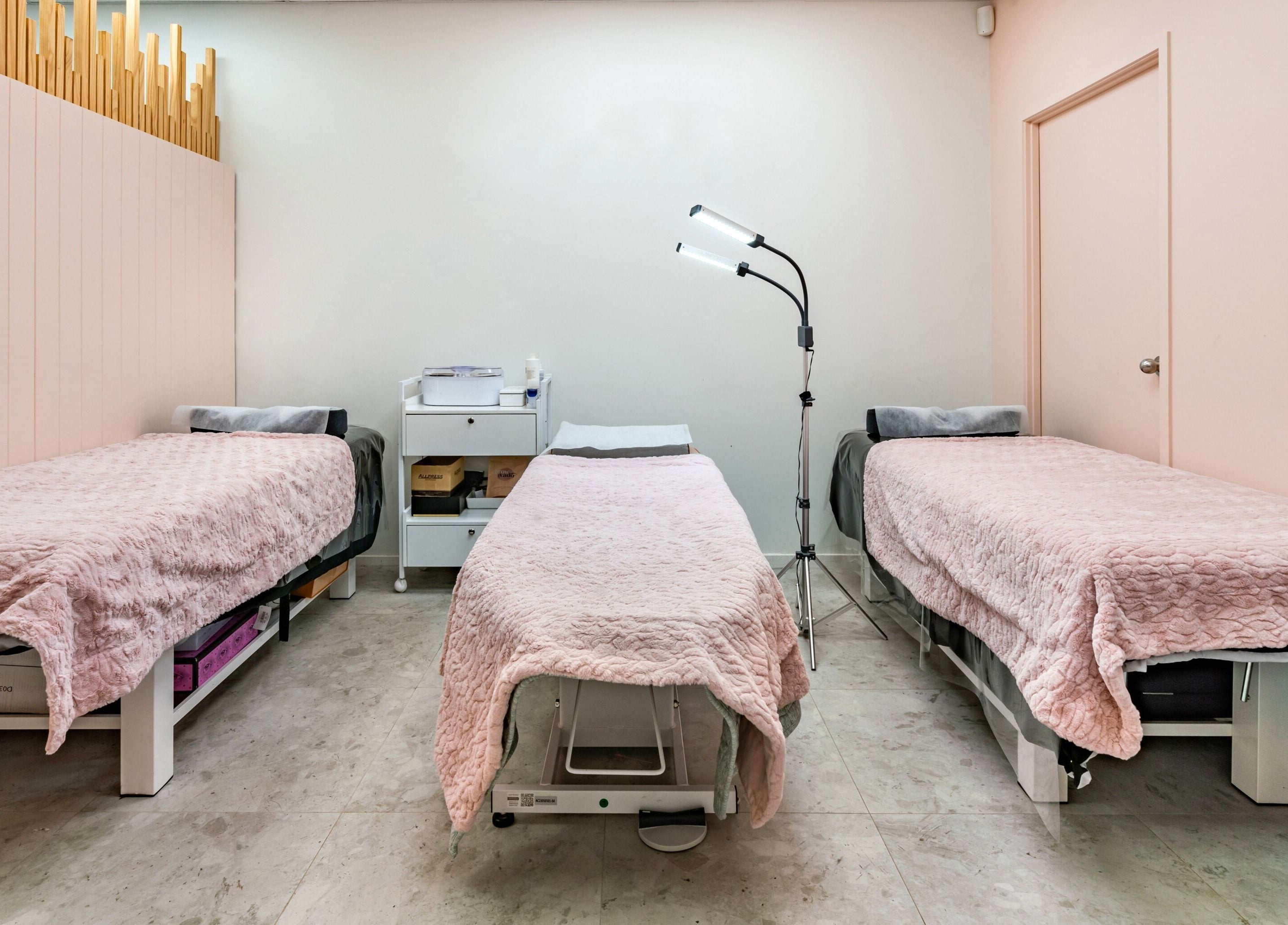 Flutter & Co spa room in Auckland, NZ with three pink-covered beds ready for treatment.