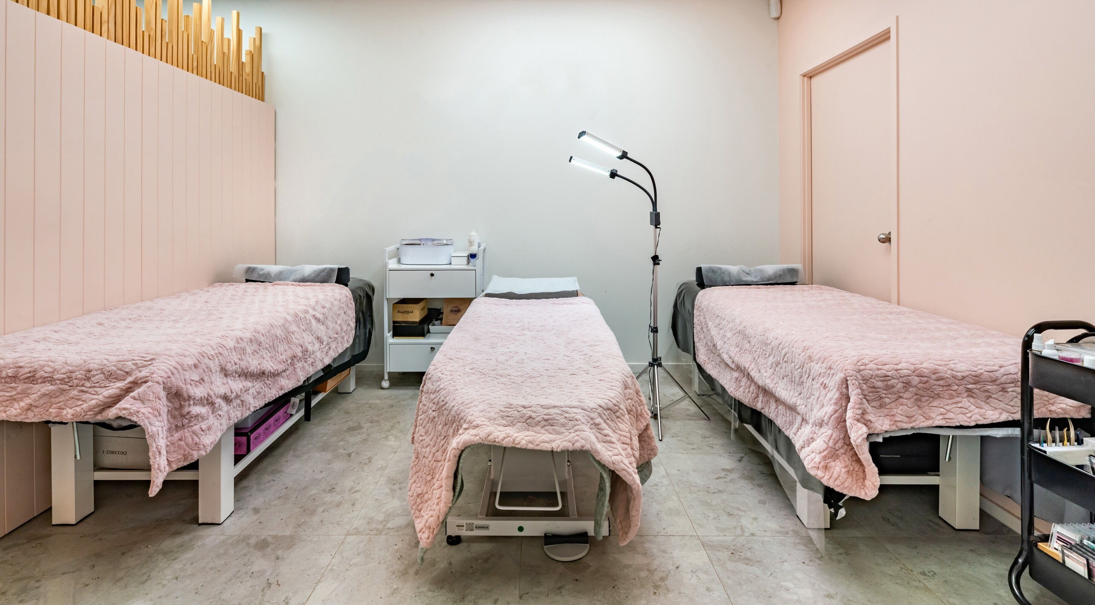 Flutter & Co spa room in Auckland, NZ with three pink-covered beds ready for treatment.
