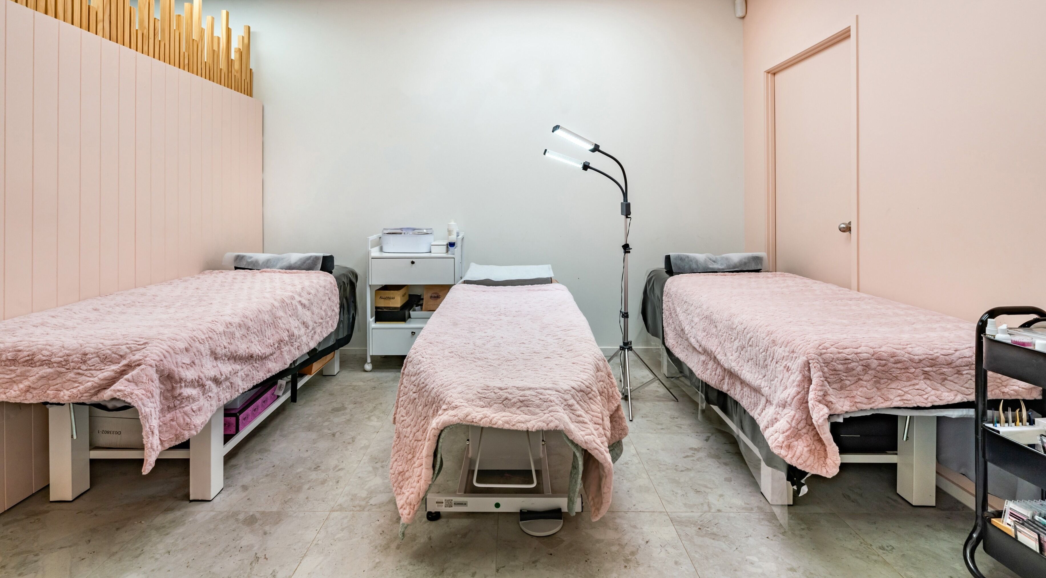 Flutter & Co spa room in Auckland, NZ with three pink-covered beds ready for treatment.
