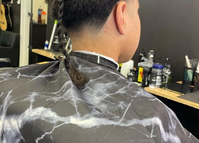 Client with braided hair at MAUI BARBERS ROTORUA seated in a modern barbershop in Rotorua, Bay Of Plenty, NZ.