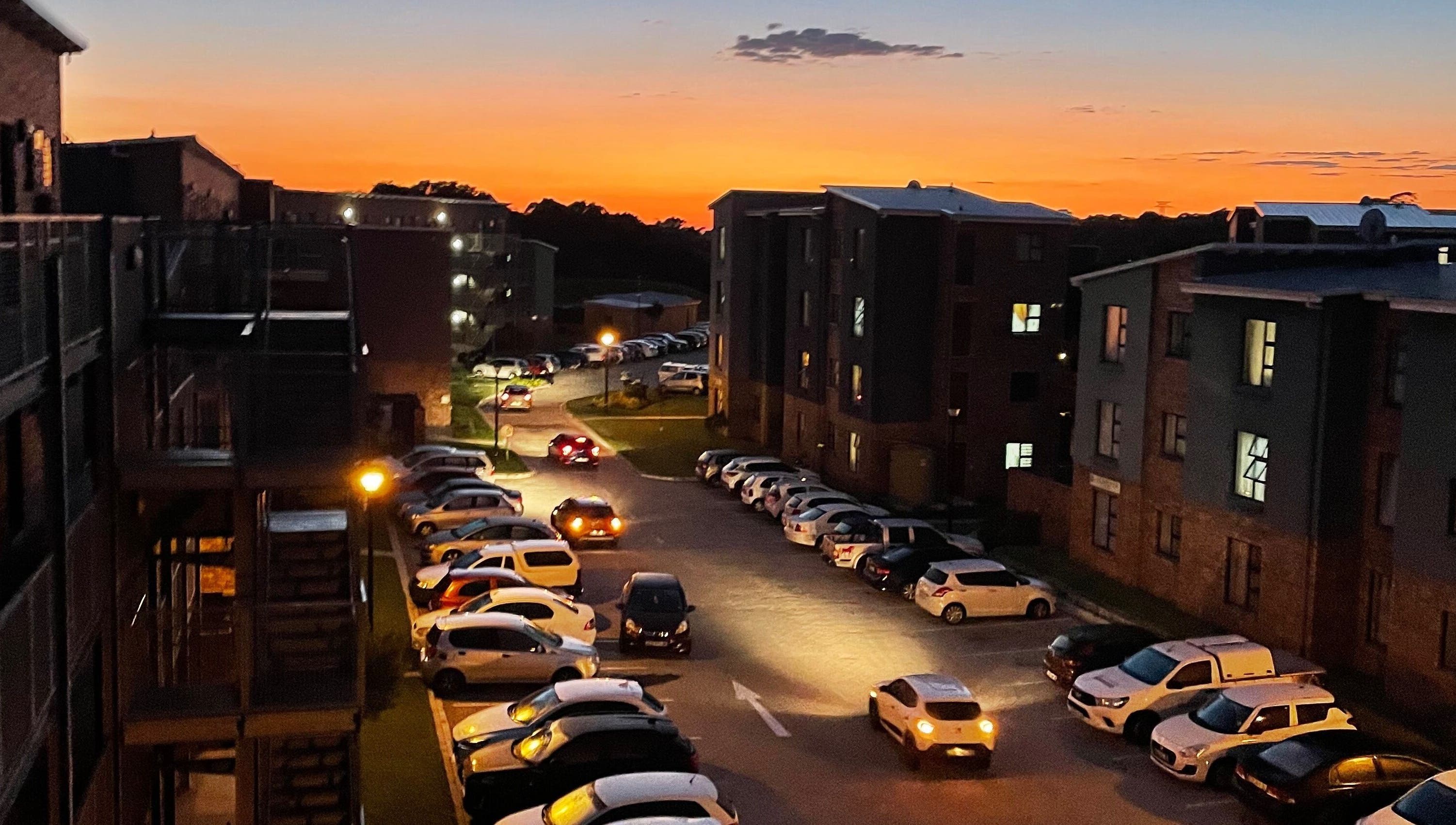 Define Artistry Nail Bar in Gqeberha, Eastern Cape, ZA, at sunset with parked cars and illuminated buildings.