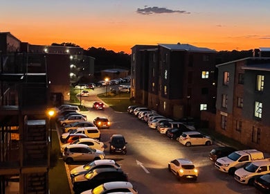 Define Artistry Nail Bar in Gqeberha, Eastern Cape, ZA, at sunset with parked cars and illuminated buildings.
