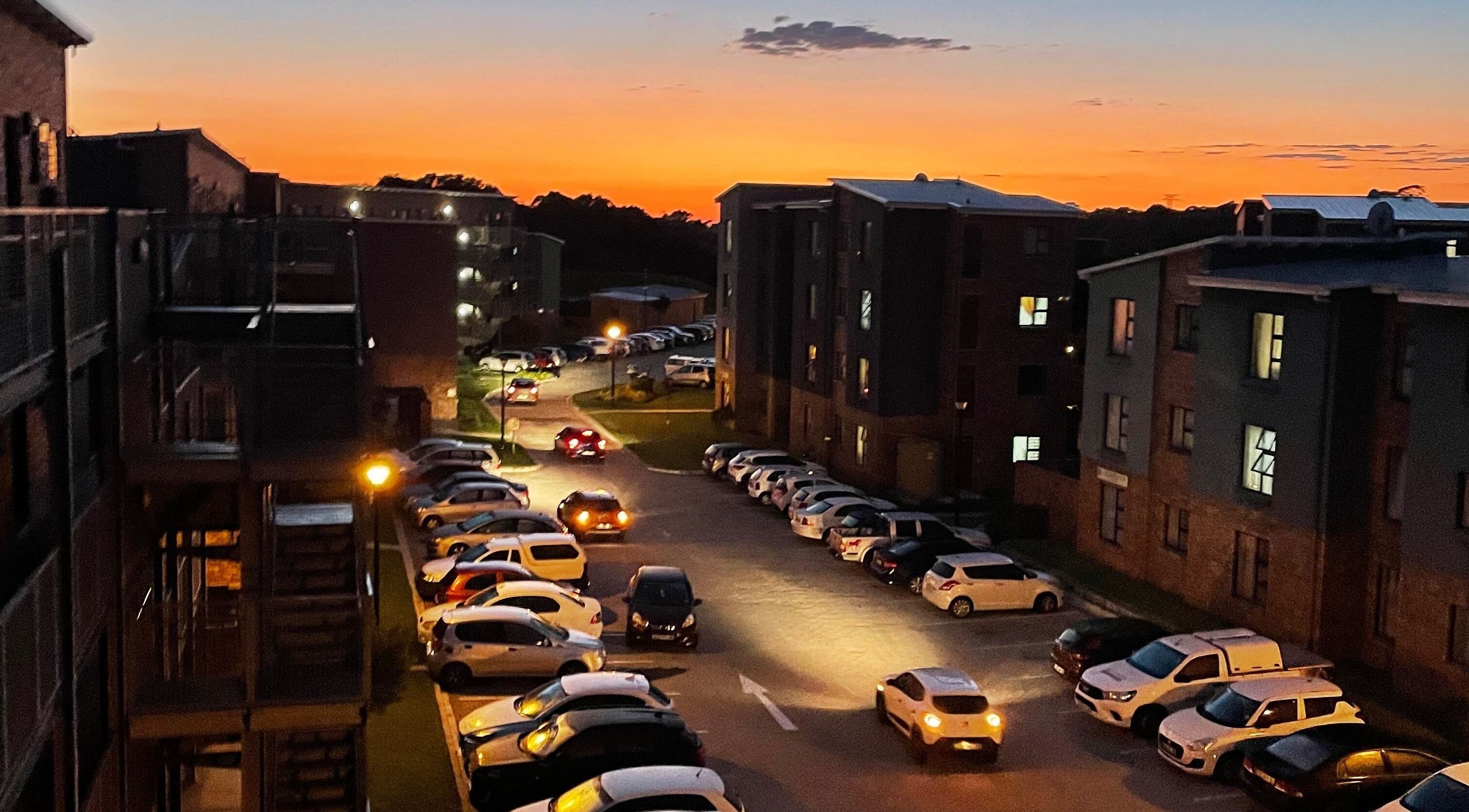 Define Artistry Nail Bar in Gqeberha, Eastern Cape, ZA, at sunset with parked cars and illuminated buildings.