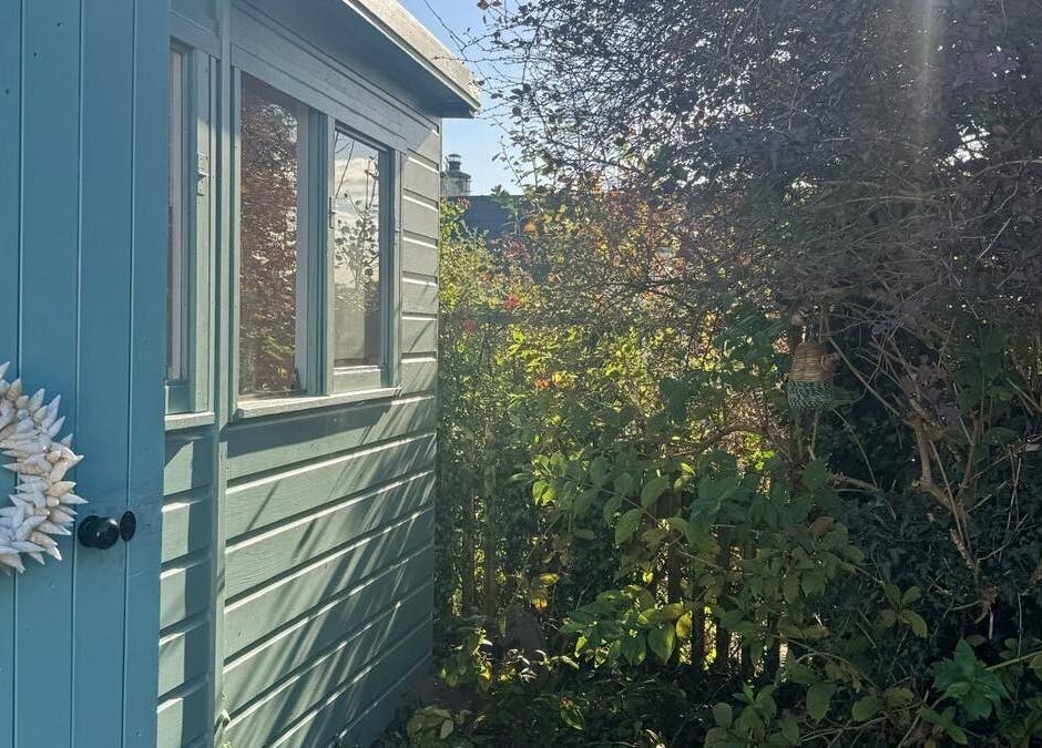 Rosie Atherton Wellbeing's outdoor area in Constantine, England, GB, featuring a blue shed and lush greenery.