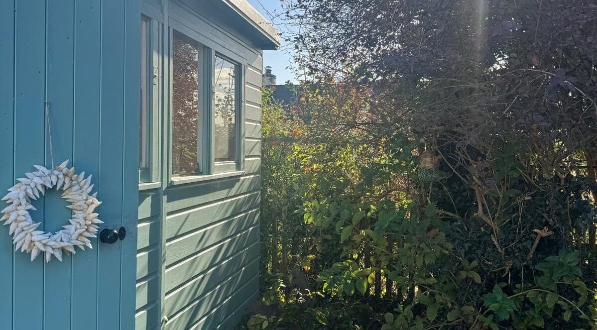 Rosie Atherton Wellbeing's outdoor area in Constantine, England, GB, featuring a blue shed and lush greenery.