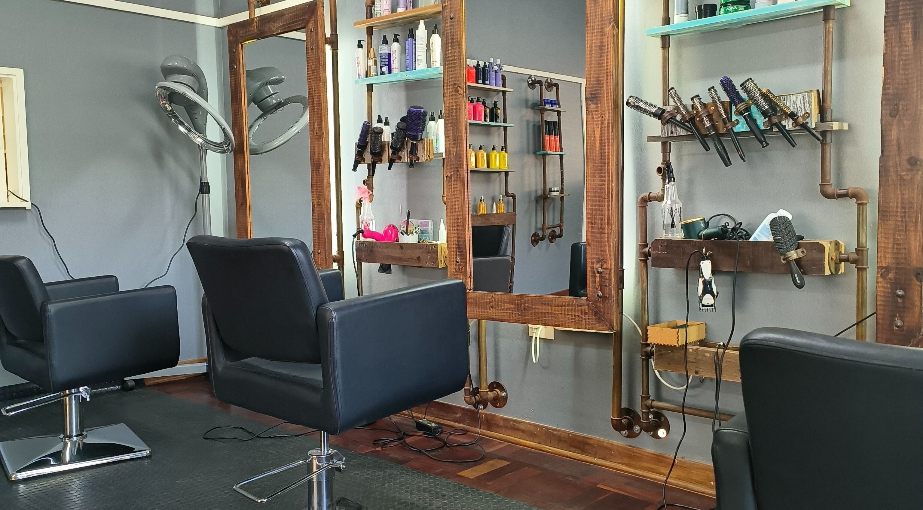 Elegant styling stations at Revive Hair Studio in Rustenburg, North West, ZA, showcasing sleek chairs and products.