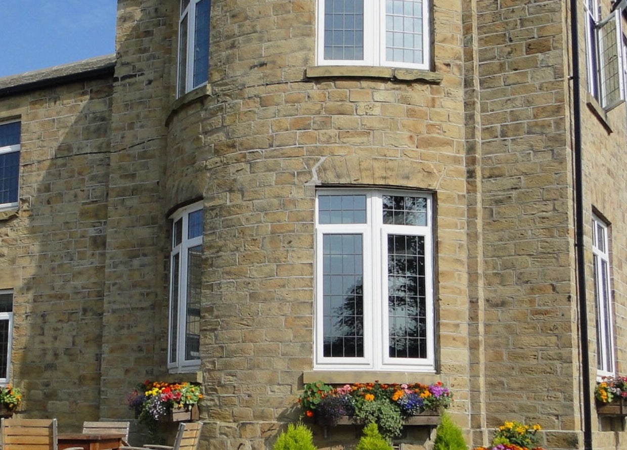 Exterior of Inner Shine healing at Iveridge Hall, Oulton, England, GB, featuring stone walls and blooming flowers.
