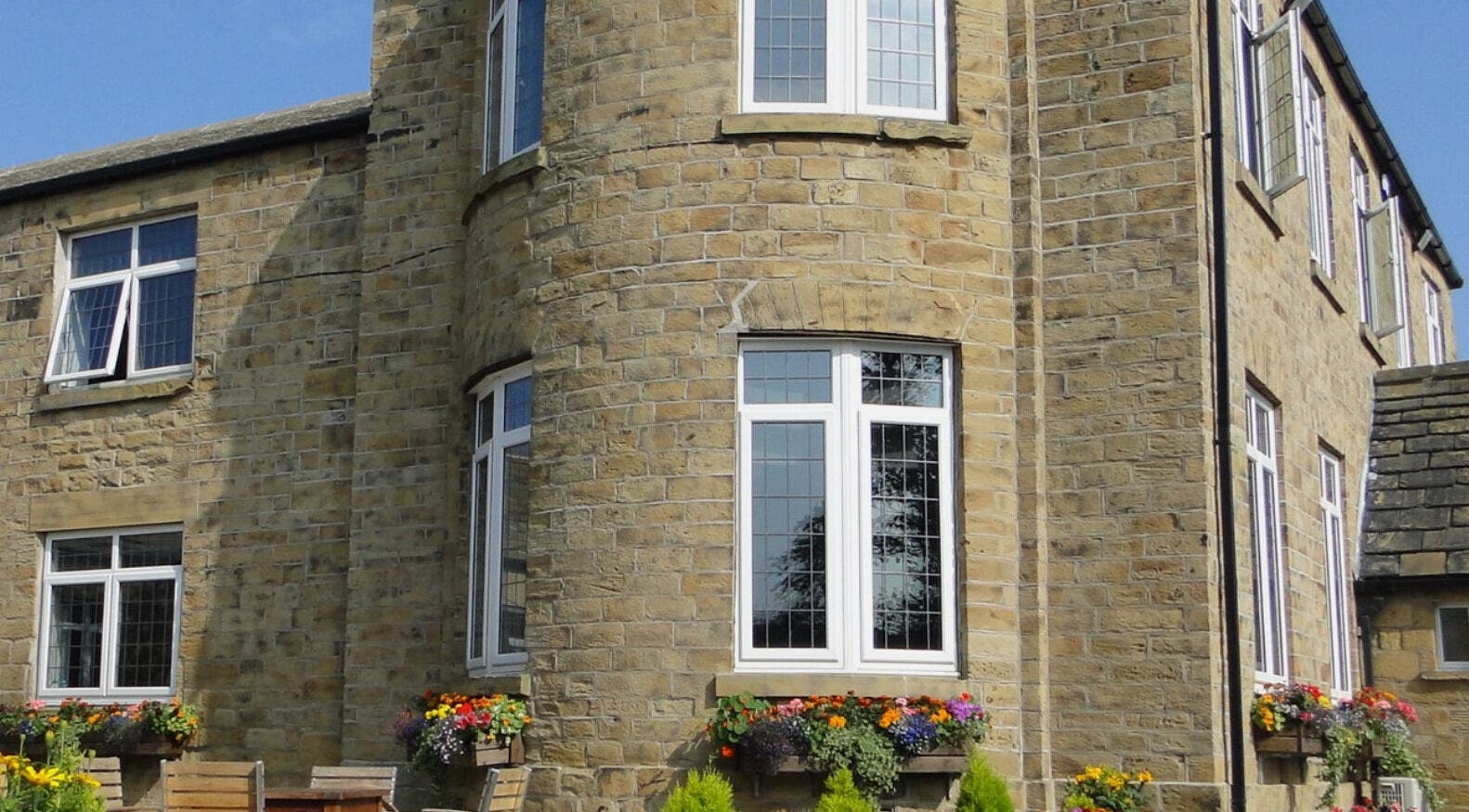 Exterior of Inner Shine healing at Iveridge Hall, Oulton, England, GB, featuring stone walls and blooming flowers.