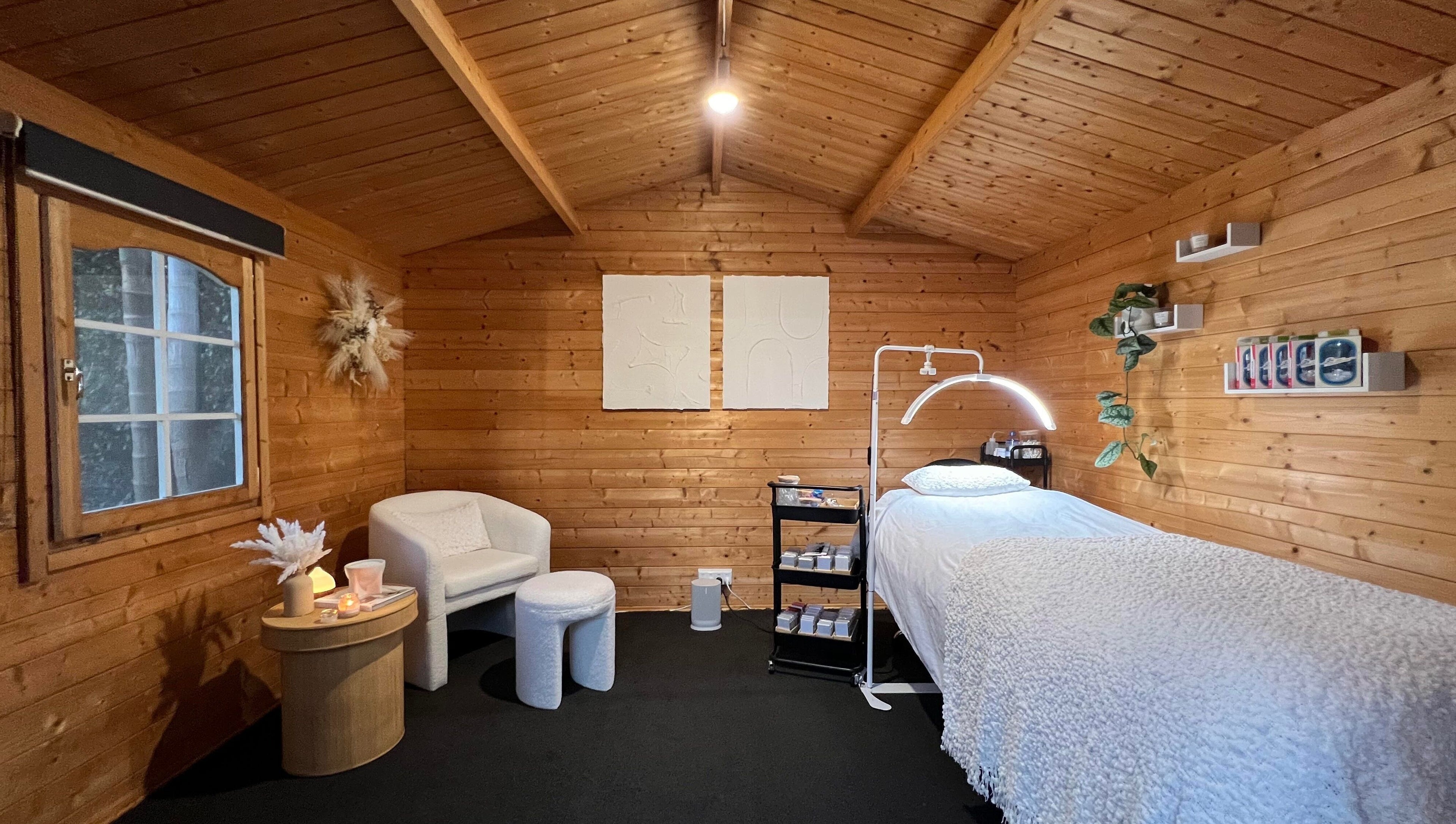 Tranquil wooden treatment room at The Eye Studio, Auckland, NZ, featuring a plush bed and serene decor.