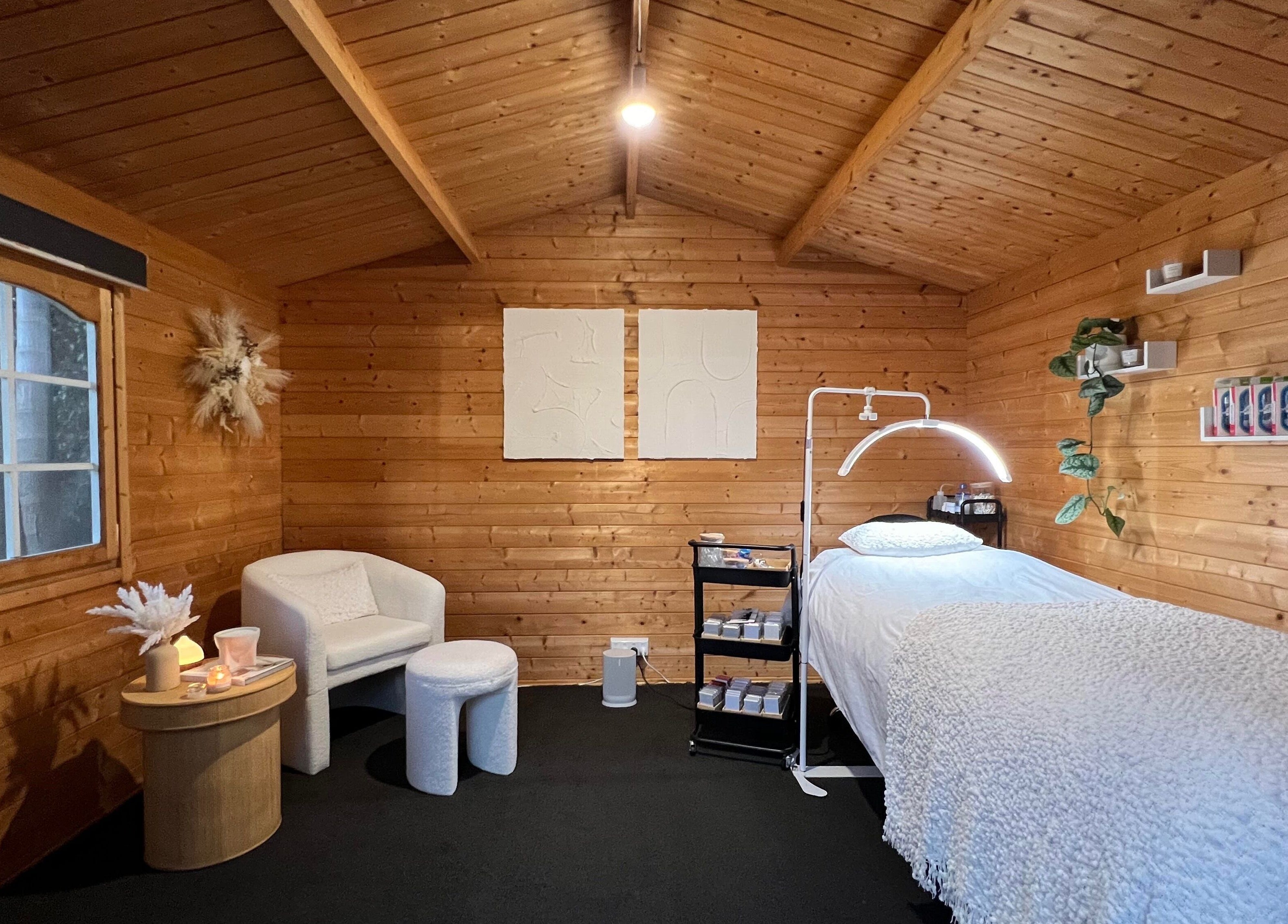 Tranquil wooden treatment room at The Eye Studio, Auckland, NZ, featuring a plush bed and serene decor.