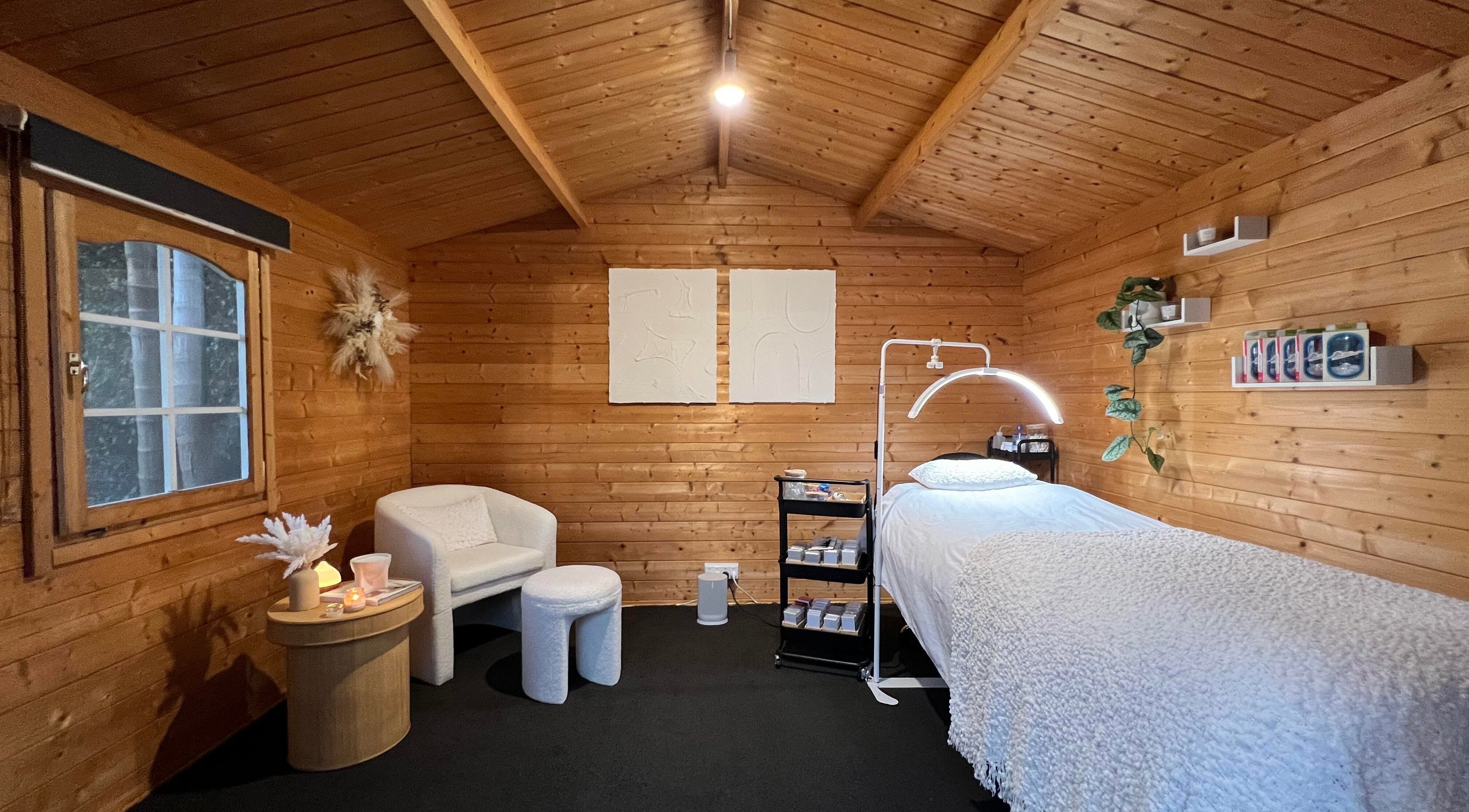 Tranquil wooden treatment room at The Eye Studio, Auckland, NZ, featuring a plush bed and serene decor.