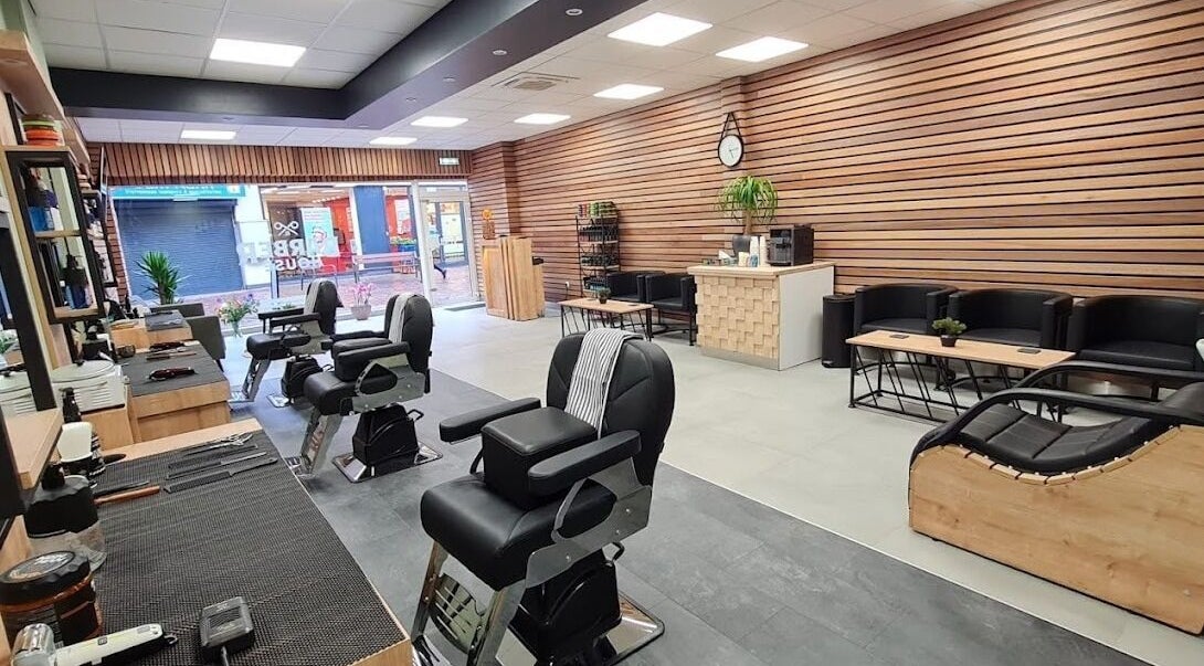 Stijlvol interieur van BarberHouse, gelegen in Ede, Gelderland, NL met moderne kappersstoelen en houtaccenten.