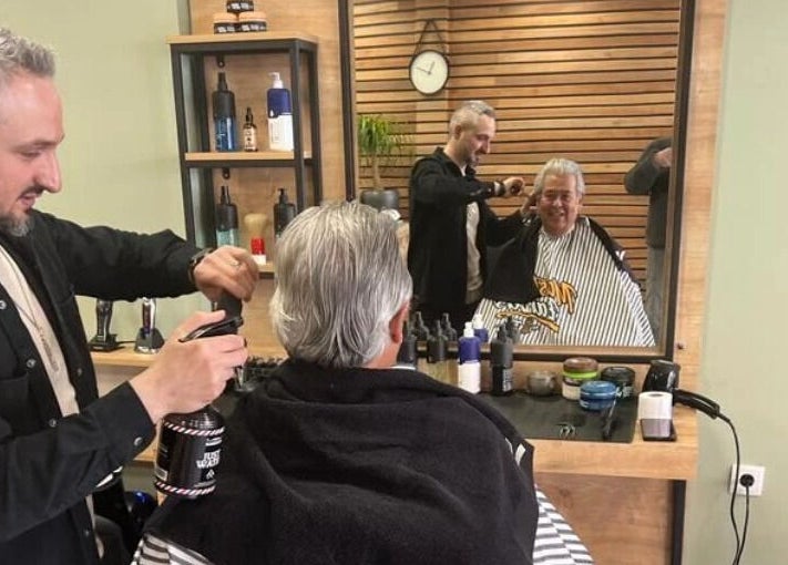 Kapper bij BarberHouse in Ede, Gelderland, NL verzorgt klant met glimlach tijdens knipbeurt.