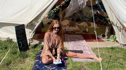 Tarot reader in front of a decorated tent at Indigo Wellness, Falmouth, England, GB, offering mystical readings.
