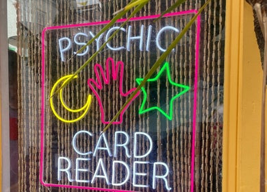 Neon psychic sign at Indigo Wellness, Falmouth, England, GB, highlighting card reading services.