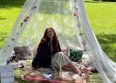 A peaceful tarot reading setup at Indigo Wellness, Falmouth, England, GB, with a woman sitting under a decorated canopy.