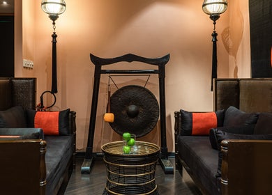 Elegant lounge with a gong at SENSASIA - The Village, Dubai, Dubai, AE. Stylish decor with black and red accents.