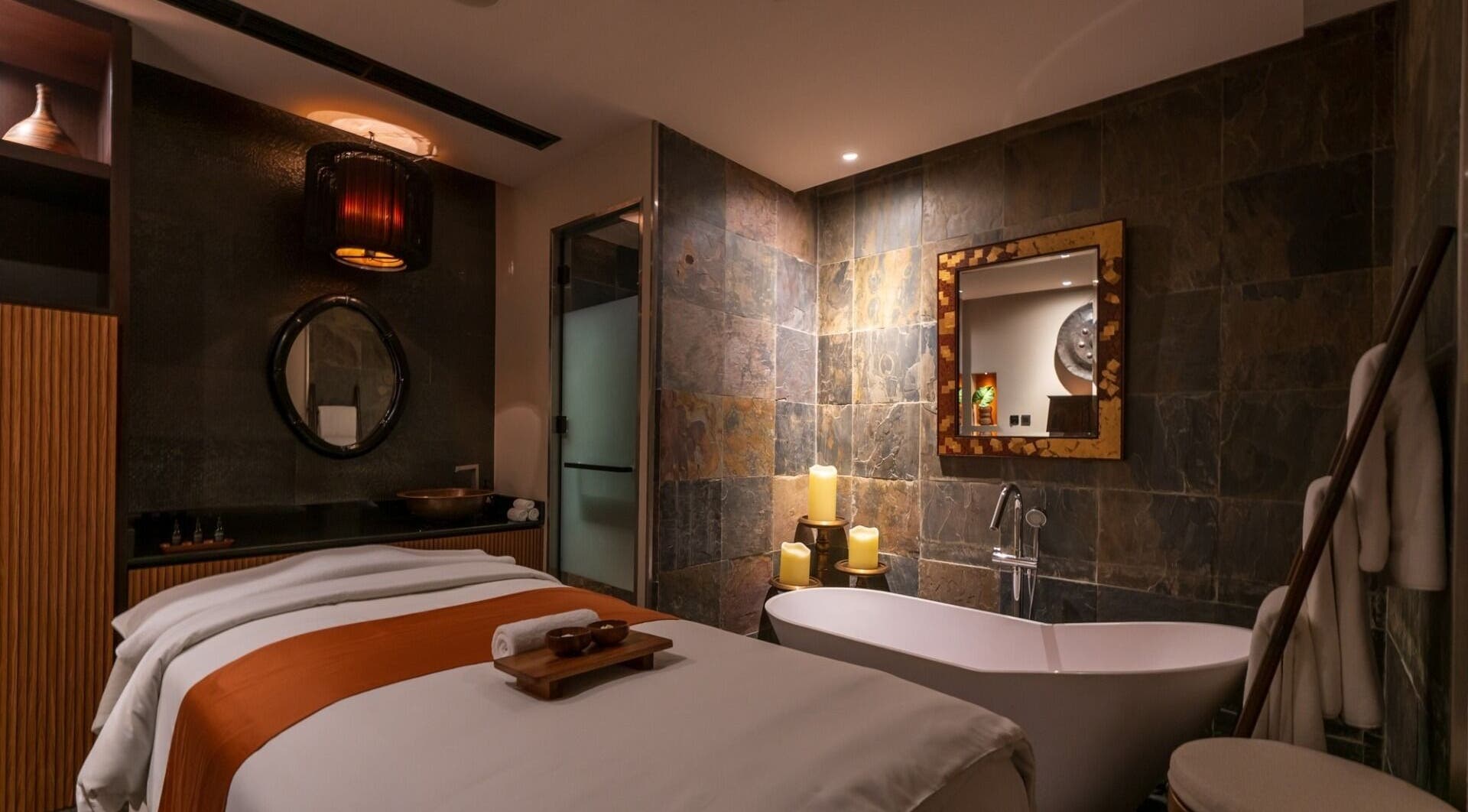 Luxurious spa room at SENSASIA - The Village, Dubai, Dubai, AE with massage table and candle-lit bathtub.
