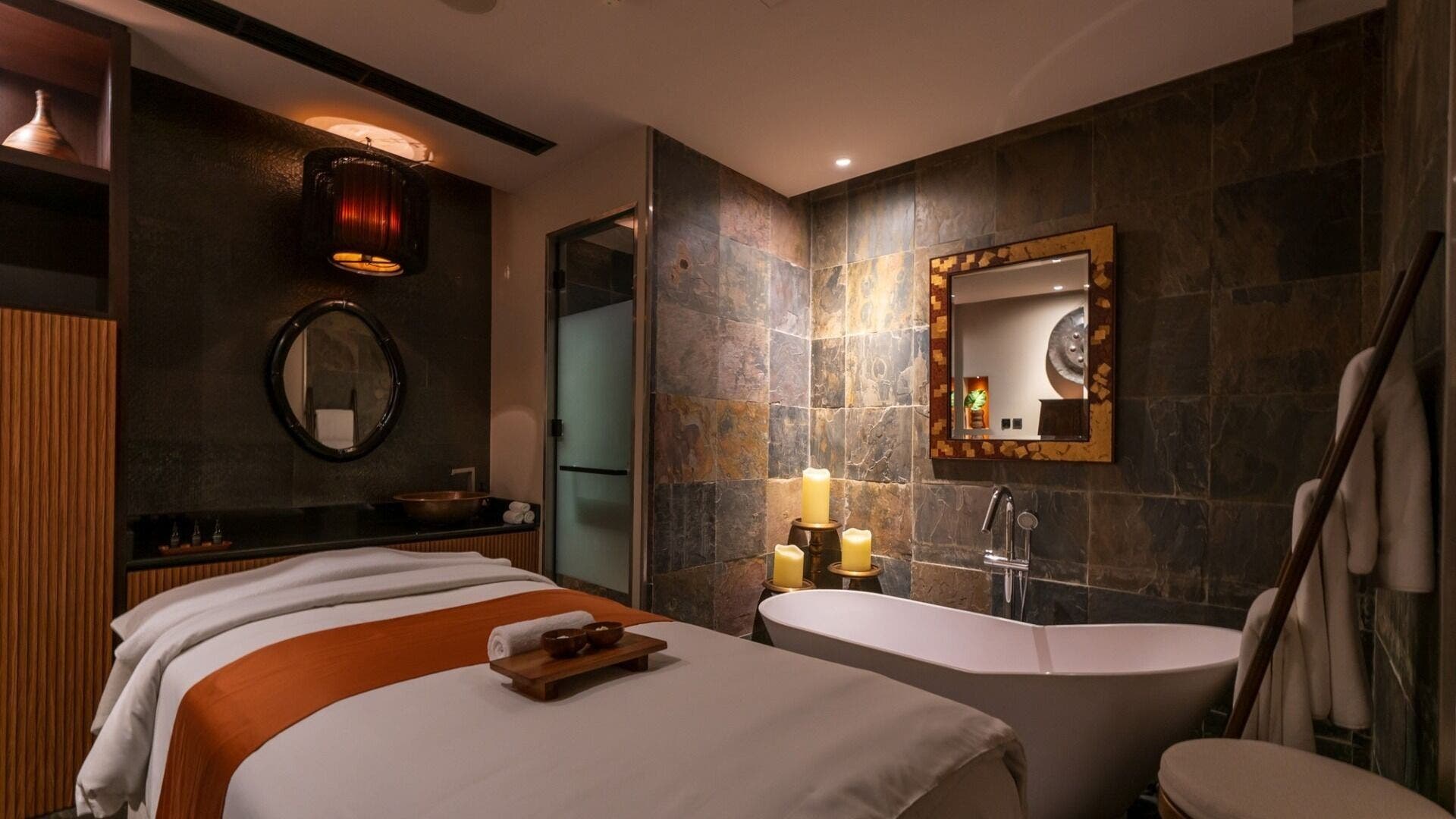 Luxurious spa room at SENSASIA - The Village, Dubai, Dubai, AE with massage table and candle-lit bathtub.