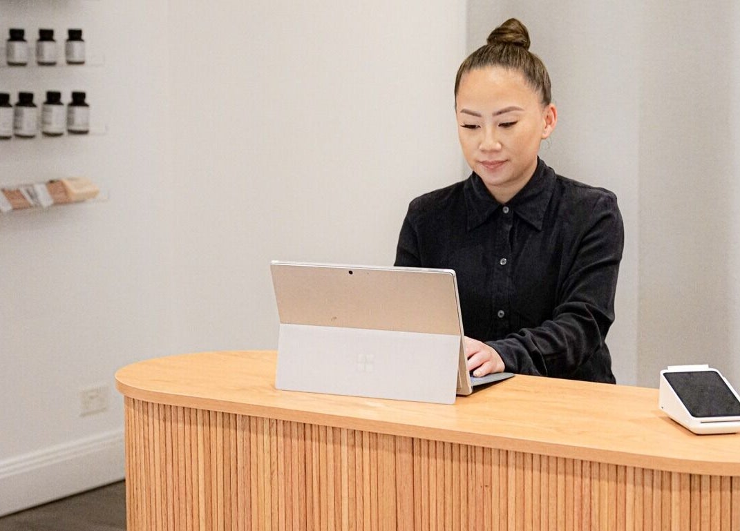 Reception area at Blanc to Noir, Canley Heights, New South Wales, AU, with a staff member using a laptop.