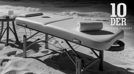 Massage table on sandy beach at 10-DER Massage Therapy, Christ Church, BB, offering relaxation by the ocean.