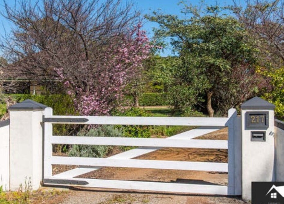White gate entrance surrounded by lush greenery at Oh Tan, Mundijong, Western Australia, AU.