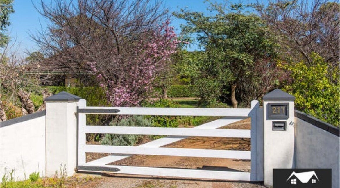 White gate entrance surrounded by lush greenery at Oh Tan, Mundijong, Western Australia, AU.