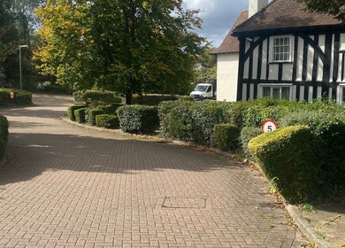 Quaint hedge-lined path near Ebbsfleet Aesthetics, Northfleet, England, GB, leading to a traditional building.