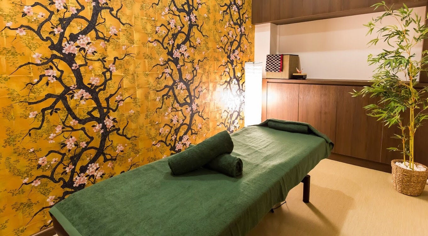 Serene massage room at Atelier Kogao Delfi Orchard, Singapore, SG with elegant floral wall design.