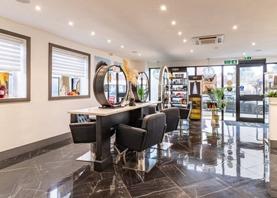 Modern interior of Maria Charles Hair Crawley, sleek black chairs and mirrors, located in Crawley, England, GB.