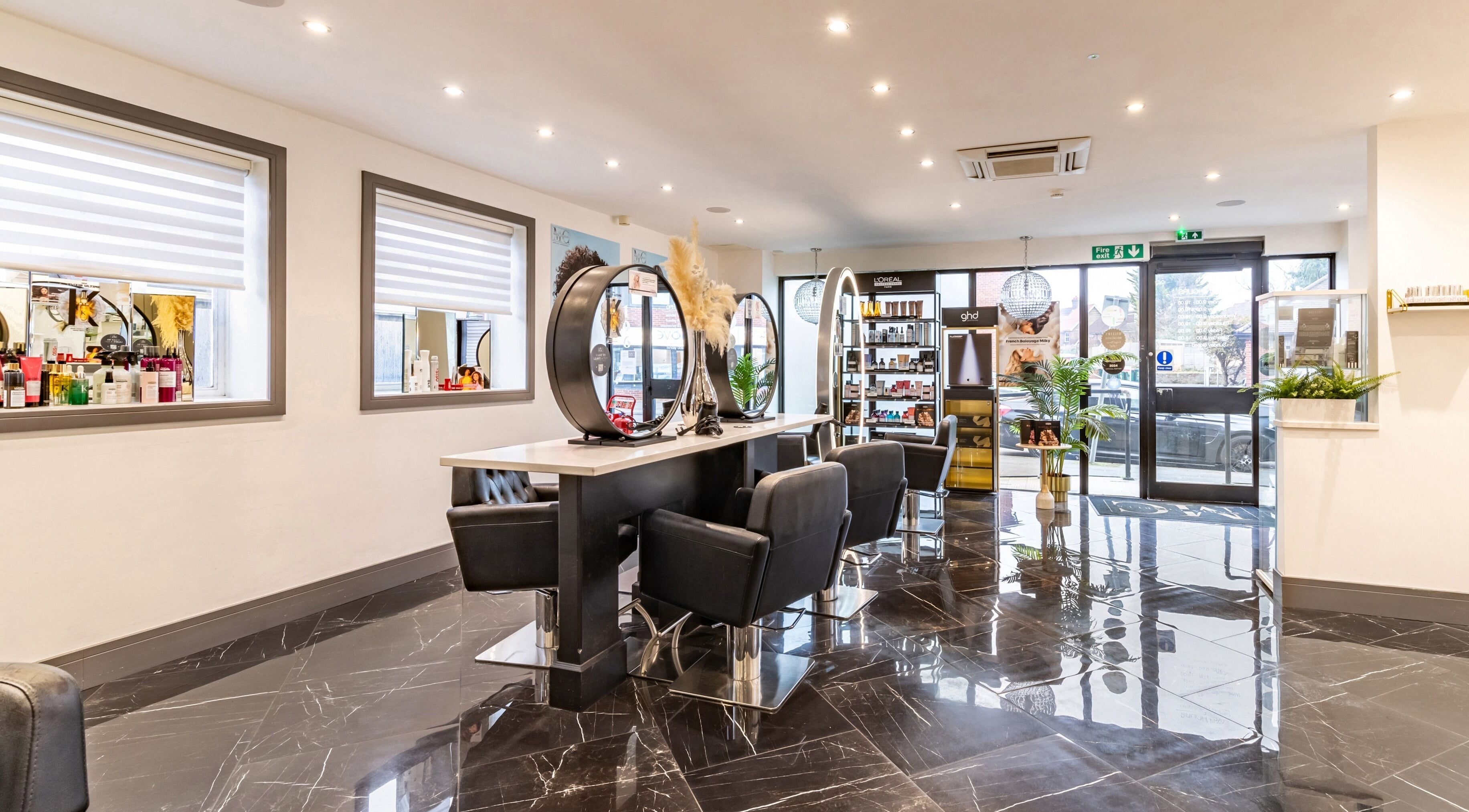 Modern interior of Maria Charles Hair Crawley, sleek black chairs and mirrors, located in Crawley, England, GB.