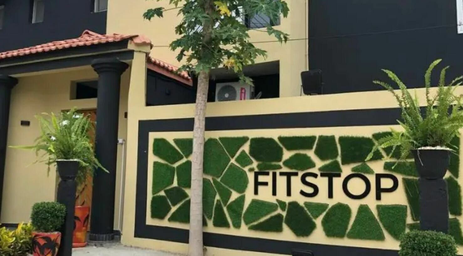 Entrée de Fitstop Sen à Dakar. Design moderne et végétation luxuriante pour détente et bien-être.