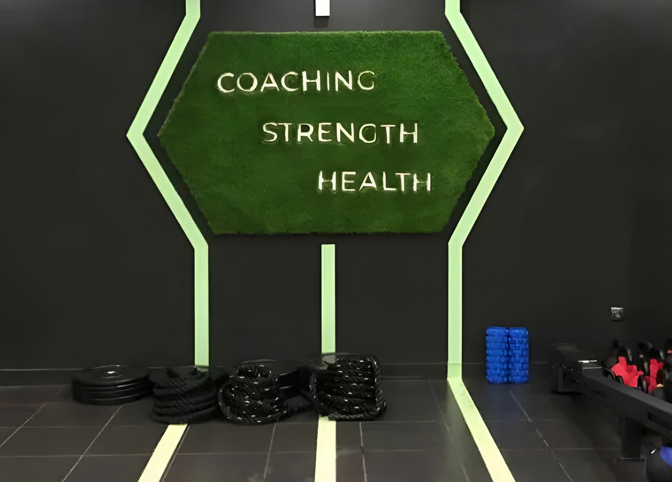 Salle d'entraînement moderne à Fitstop Sen, Dakar, avec équipement et mur vert inspirant.