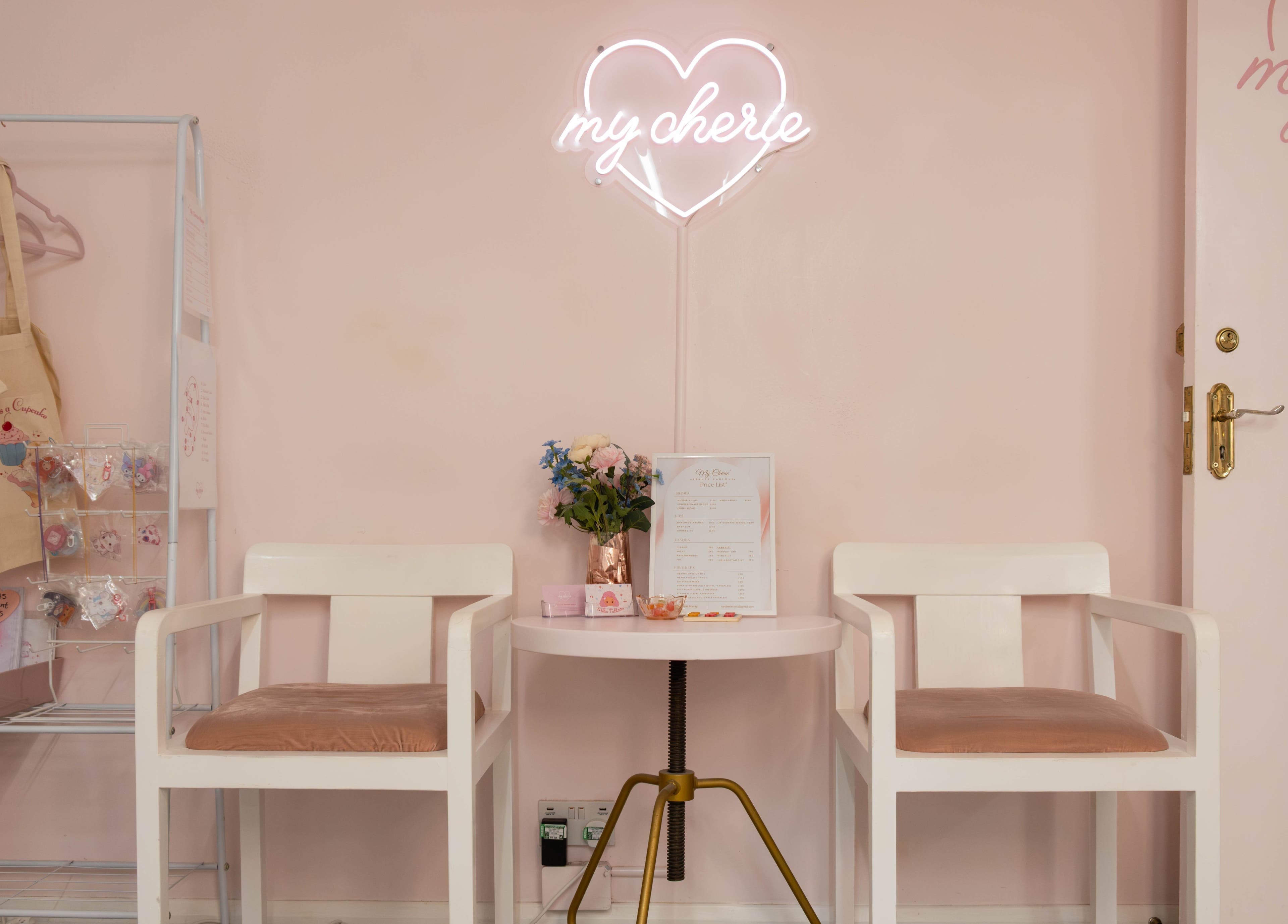 Elegant seating at My Cherie Studio, London, England, GB, with neon sign and flowers.