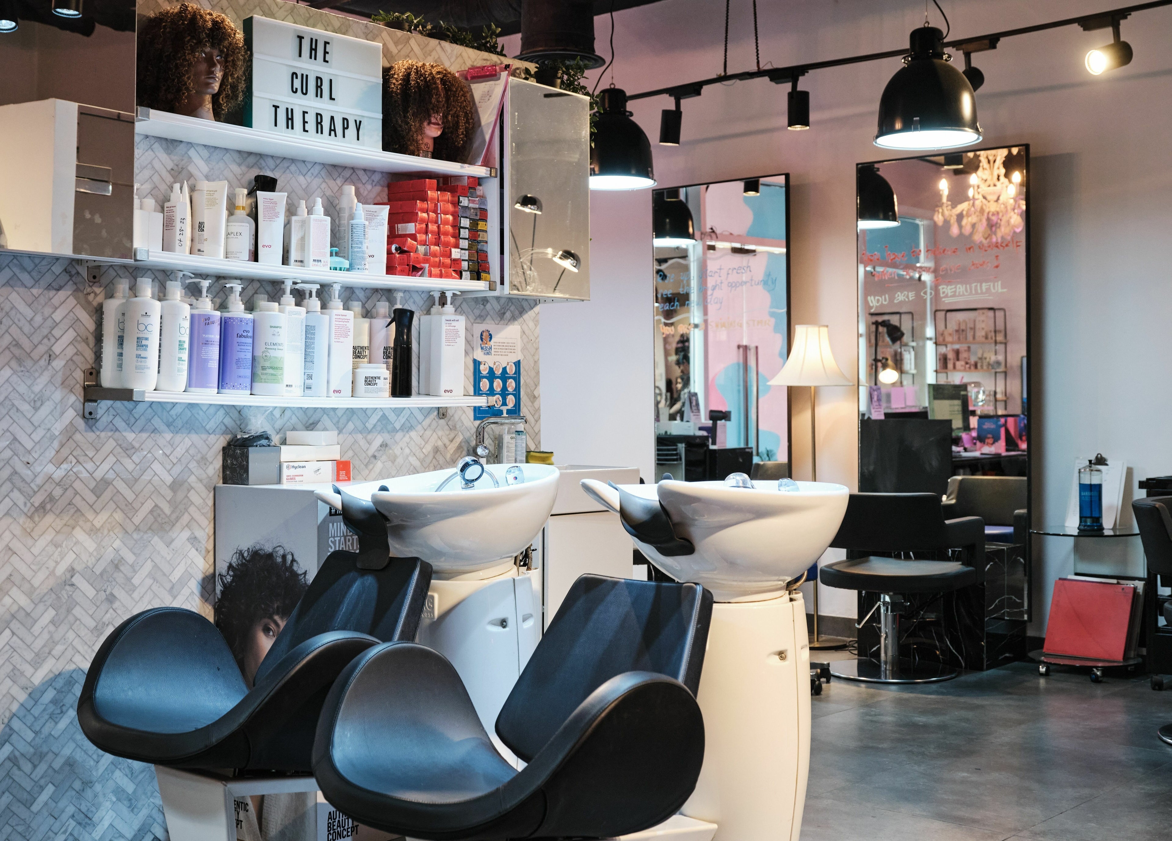 Stylish interior of The Curl Therapy in Dubai, Dubai, AE featuring modern salon chairs and hair products.