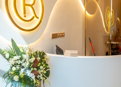 Recepção elegante do Resolve Hair em Dubai, Dubai, AE com arranjo floral e logo iluminado.