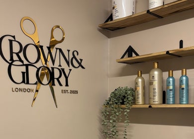 Crown and Glory salon in Wembley, England, GB showcases elegant products and decor on wooden shelves.