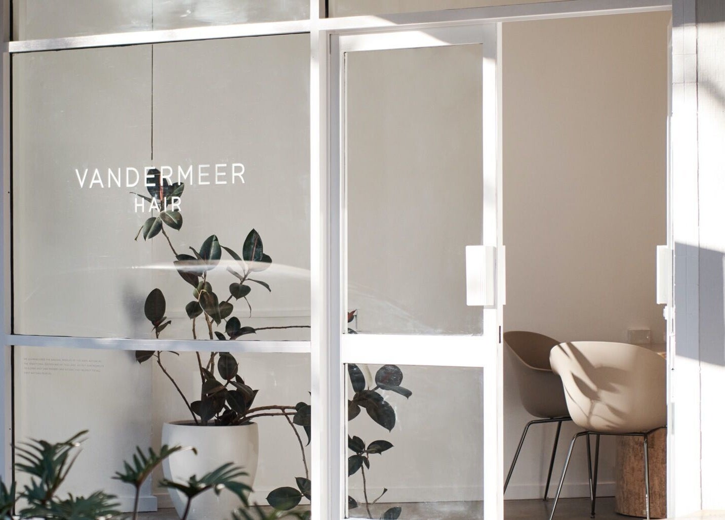 Front entrance of Vandermeer Hair, Surry Hills, New South Wales, AU with glass doors and minimalist decor.
